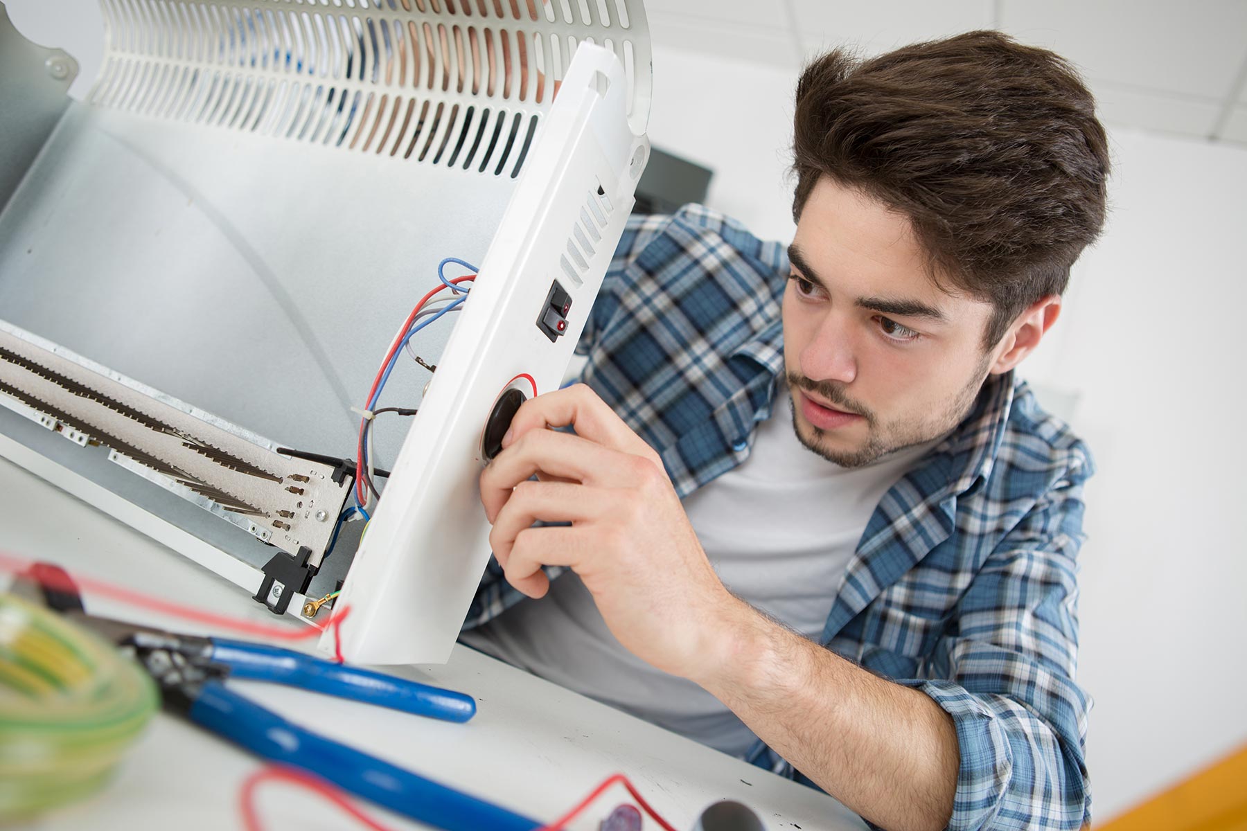 young-male-plumber-examining-electric-heater-PLXD3ZH-3.jpg